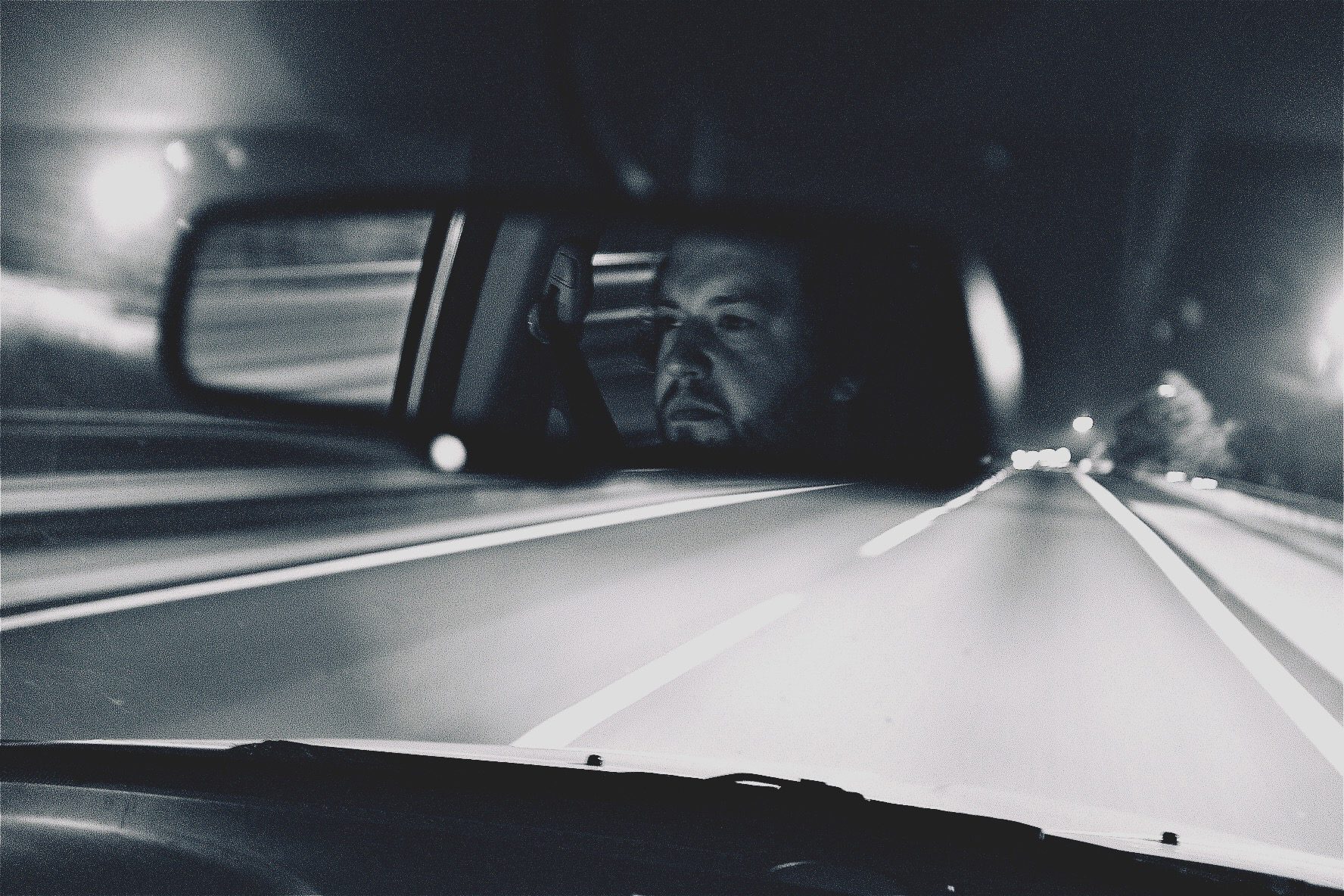 Night highway, the driver's face in the rearview mirror